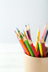 Fototapeta premium Colorful pencils in cup on white wooden background