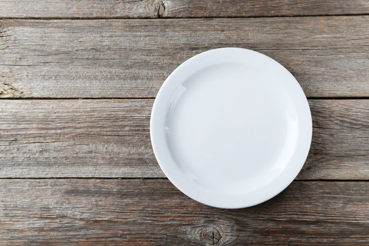 Empty white plate on grey wooden background