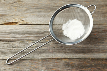 Silver sieve with flour on grey wooden background