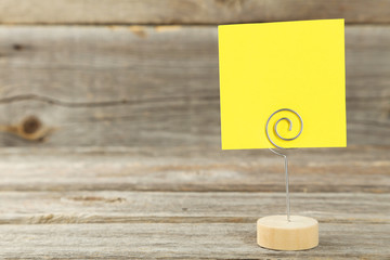 Yellow note paper on a holder on grey wooden background