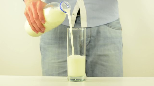 Man pours milk into a glass - white background studio