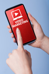 Man presses a touch screen smart phone with the symbol of video