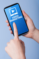Man presses a touch screen smart phone with the symbol of video