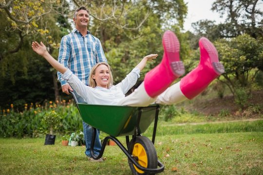 Happy couple playing with a wheelbarrow 