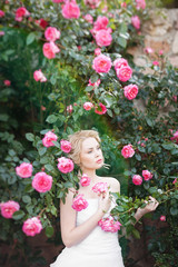 Obraz na płótnie Canvas Attractive young bride posing near roses garden