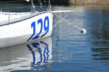 Reflet d'un voilier de course dans l'eau.