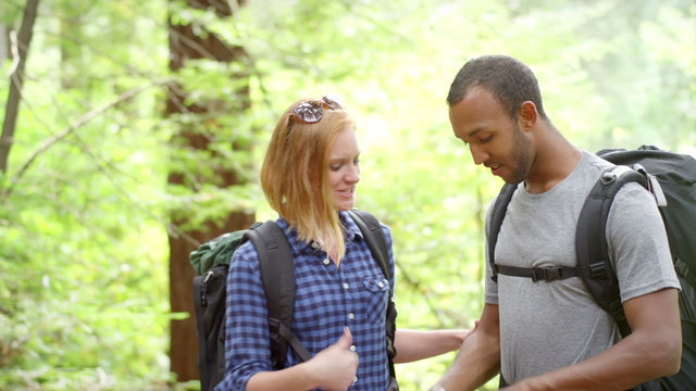 A couple on a hike in the forest, stop in the middle of the trail and take a picture of something in the distance