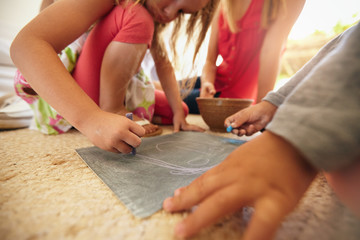 Little girl drawing with her brother and parents