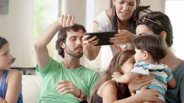 Family taking pictures with a tablet computer in living room