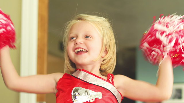 A young girl is dressed like a cheerleader and jumps up and down