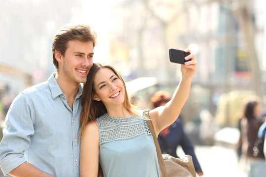 Couple of tourists photographing a selfie in a city street
