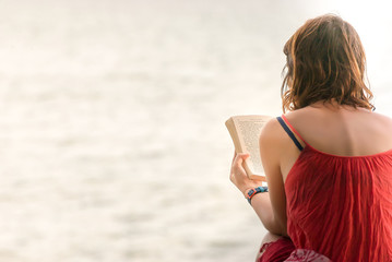 Hands of woman holding a book read beside the sea