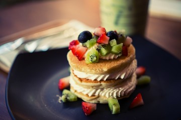 Pancakes, fruit, kiwi, strawberry berry sauce and strawberry.