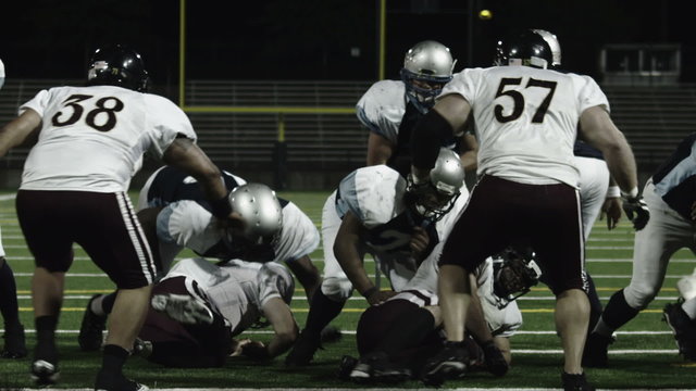 A running back takes a hand off from the QB dives over the line of scrimmage 