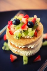 Pancakes, fruit, kiwi, strawberry berry sauce and strawberry.