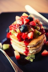 Pancakes, fruit, kiwi, strawberry berry sauce and strawberry.