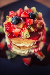 Pancakes, fruit, kiwi, strawberry berry sauce and strawberry.