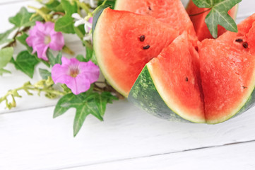 Fresh watermelon on white wooden table with flowers