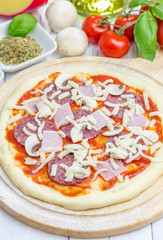 Pizza dough with salami, bacon, mushrooms and cheese