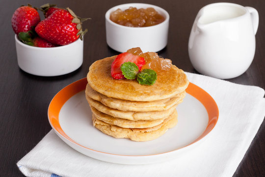 Delicious pancakes with fresh strawberries on a plate, jam and m