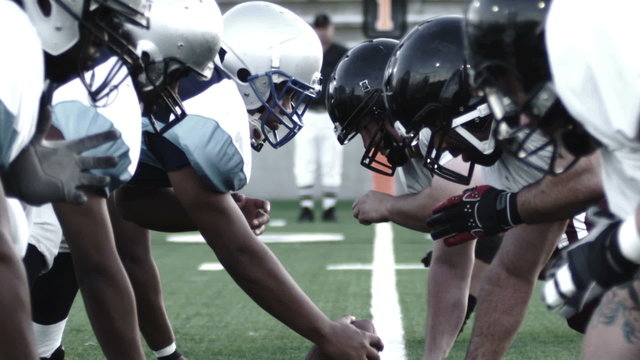 Close up of football players, linemen lining up and snapping the ball 