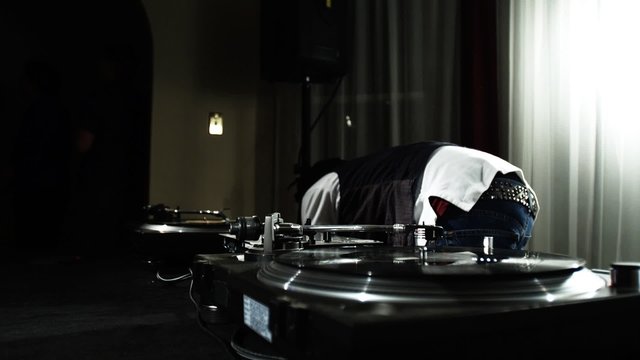 Dj changes and spins records at house party._