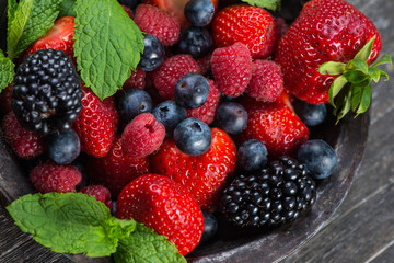 Fresh summer berries with mint in rustic bowl