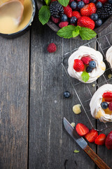 Decorating homemade pavlova meringue with berries fruit