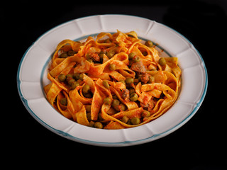 Bowl of noodles with sauce of peas on a black background