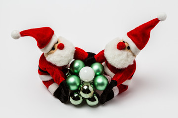 Zwei Weihnachtsmaenner halten Weihnachstkugeln fest