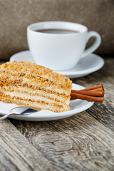 Tasty honey cake with cup of coffee on wooden background.