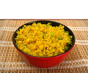 Bowl of rice with vegetables on bamboo mat