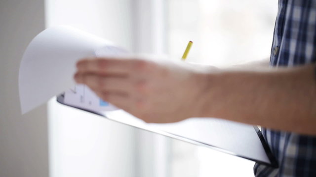 close up of man looking and writing to clipboard