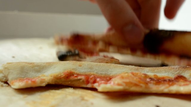 man eats pizza leftovers from pizza box - closeup
