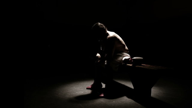 Mixed martial arts athlete sitting on a bench untangles wrapping tap