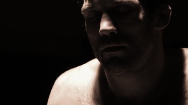 Athlete stretches his neck while sitting on a bench. Close up shot.