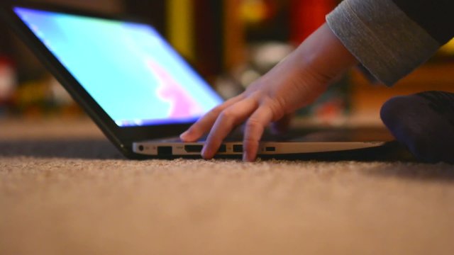 child (young boy) works on notebook - closeup laptop (hands)