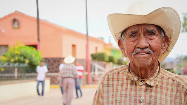 A old Mexican cowboy poses for the camera in a small town in Mexico