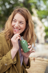lachende frau trinkt einen grünen smoothie