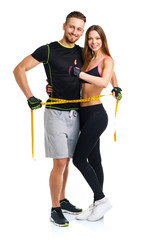 Happy athletic couple - man and woman with measuring tape on the
