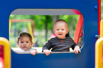 Fototapeta na wymiar Cute babies in toy car on the playground