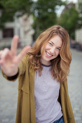 lachende junge frau zeigt zwei finger in die kamera