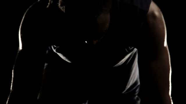 An African American athlete readies himself in the starting position 
