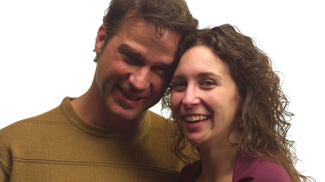 Couple smiles and hold each other while looking into the camera