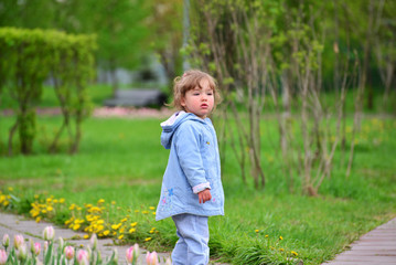 Cute baby girl with blonde curly hair outdoors.