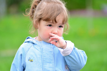 Cute baby girl with blonde curly hair outdoors.