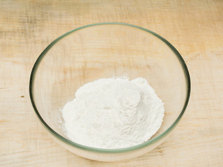 Flour in a bowl on a wood background