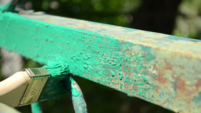 A hand paints metal gate