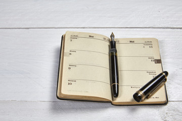 Antike Füllfeder und alter Kalender auf weißem Schreibtisch