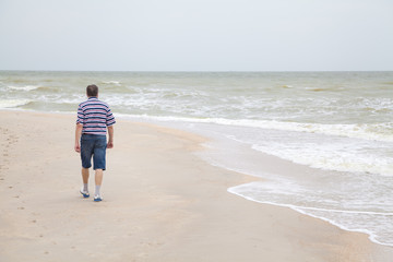 Man walks on the sea beach